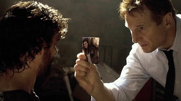 Bryan Mills in Taken holding a photograph of his daughter towards the person he believes has taken her.